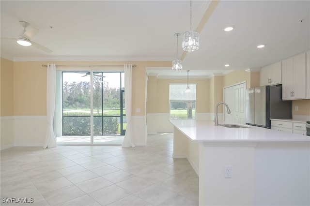 kitchen featuring white cabinetry, sink, stainless steel fridge, decorative light fixtures, and ornamental molding