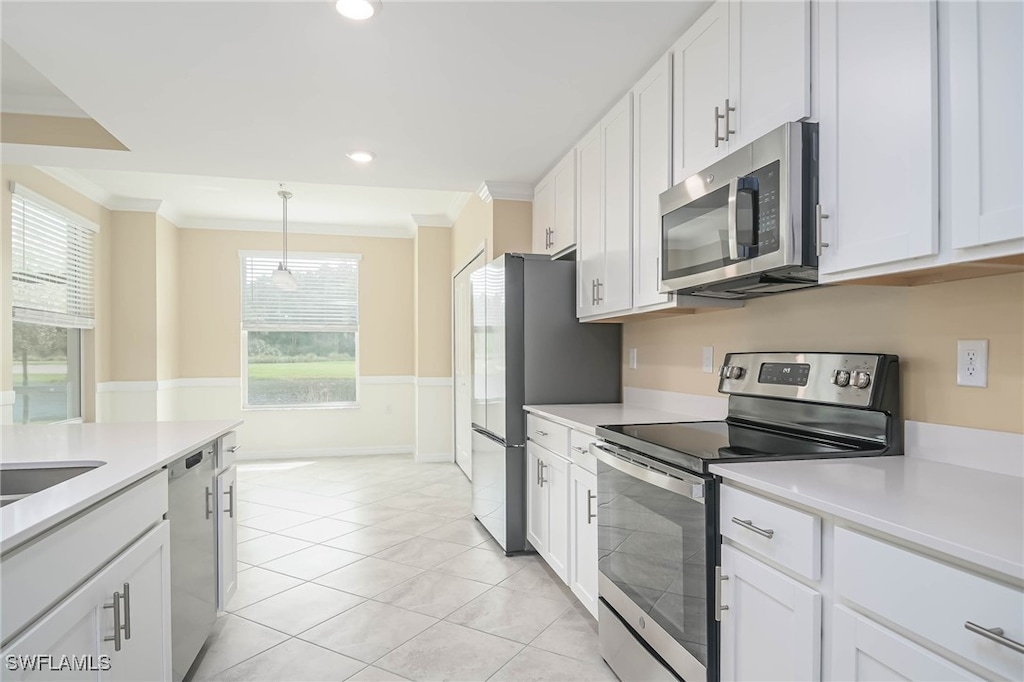 kitchen featuring ornamental molding, stainless steel appliances, white cabinetry, hanging light fixtures, and light tile patterned flooring