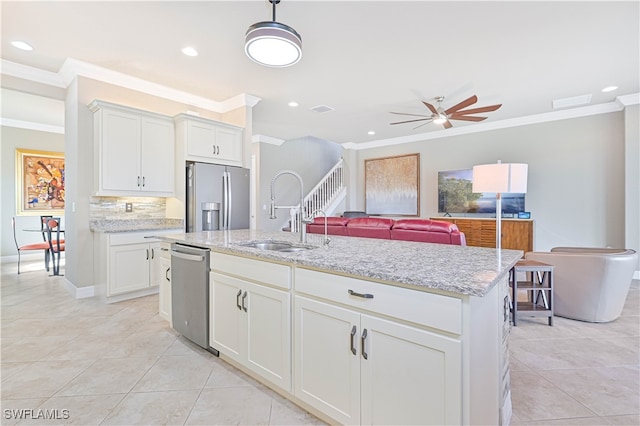 kitchen with white cabinetry, stainless steel appliances, sink, and a kitchen island with sink