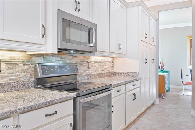 kitchen featuring white cabinets, backsplash, light tile patterned flooring, crown molding, and stainless steel appliances