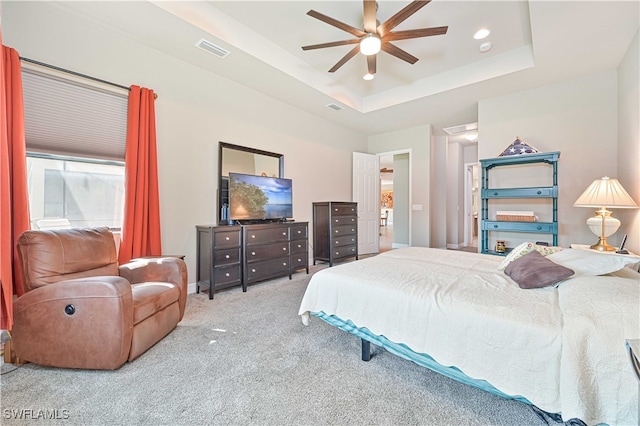 carpeted bedroom featuring a raised ceiling and ceiling fan