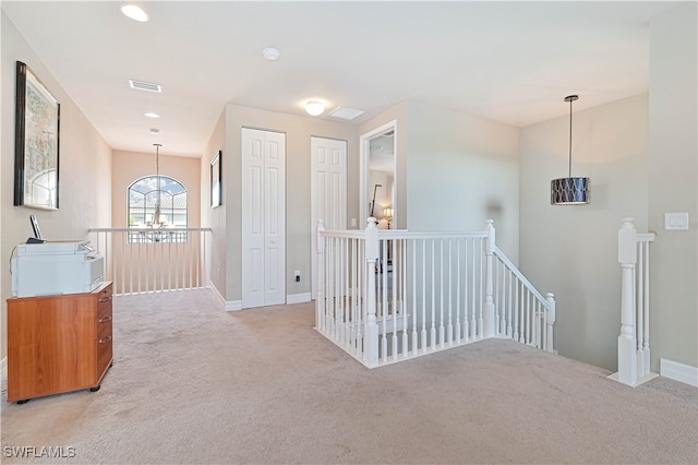 hallway featuring light carpet and a chandelier