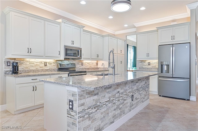 kitchen featuring ornamental molding, appliances with stainless steel finishes, a kitchen island with sink, and white cabinetry