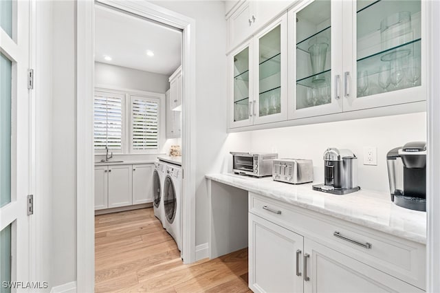 laundry room featuring cabinets, light hardwood / wood-style flooring, washer and dryer, and sink