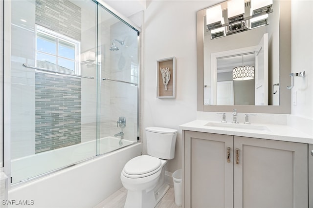 full bathroom featuring toilet, bath / shower combo with glass door, and vanity