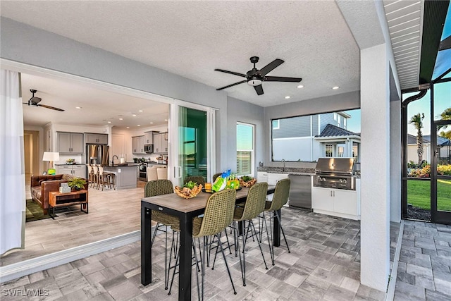 dining room featuring a textured ceiling, ceiling fan, sink, and light hardwood / wood-style flooring