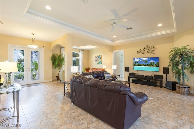 tiled living room with a raised ceiling, french doors, crown molding, and ceiling fan