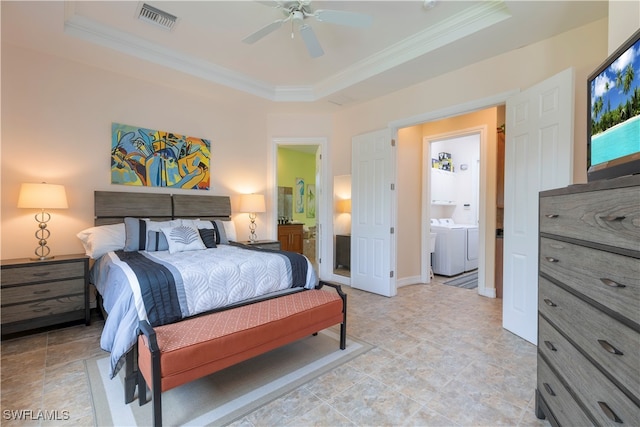 bedroom featuring ceiling fan, washing machine and clothes dryer, crown molding, a tray ceiling, and ensuite bath