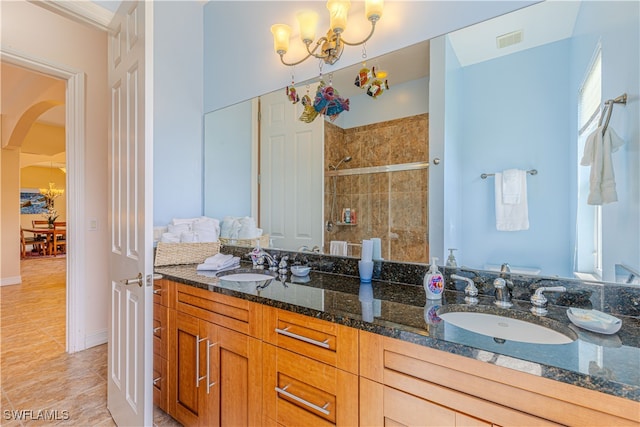 bathroom featuring an inviting chandelier, vanity, a tile shower, and wood-type flooring