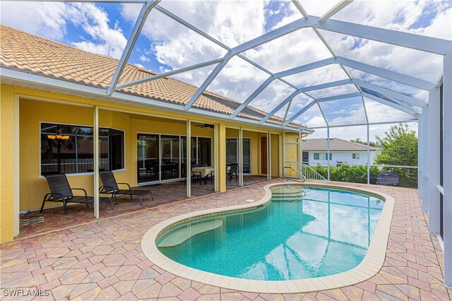 view of swimming pool with glass enclosure, ceiling fan, and a patio