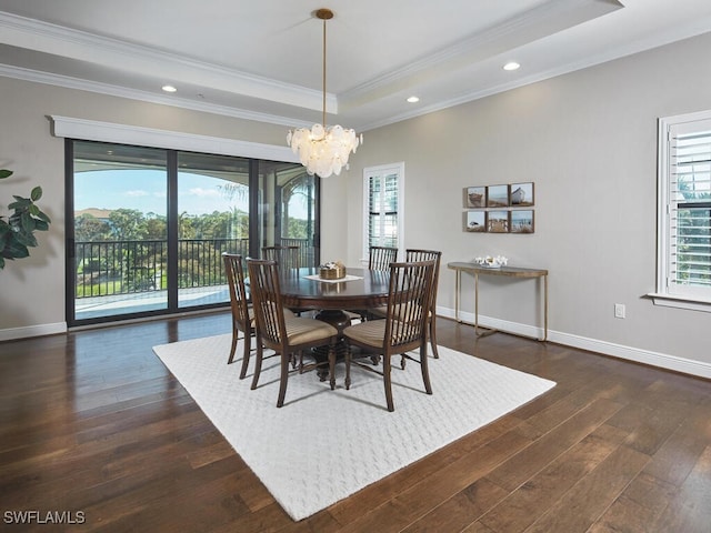 dining room featuring dark wood-type flooring, ornamental molding, a notable chandelier, and a raised ceiling