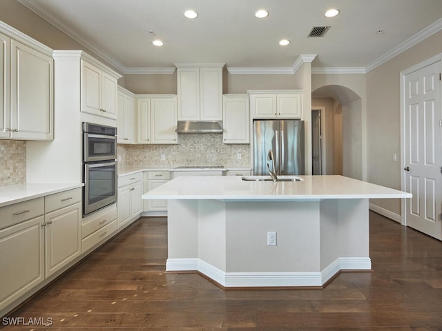 kitchen featuring sink, tasteful backsplash, a kitchen island with sink, dark wood-type flooring, and appliances with stainless steel finishes