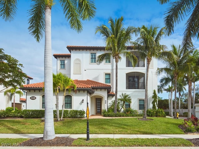 mediterranean / spanish-style house featuring stucco siding, a tiled roof, and a front yard