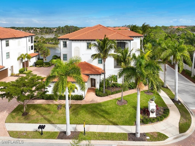 mediterranean / spanish-style home featuring stucco siding, a tile roof, and a front yard
