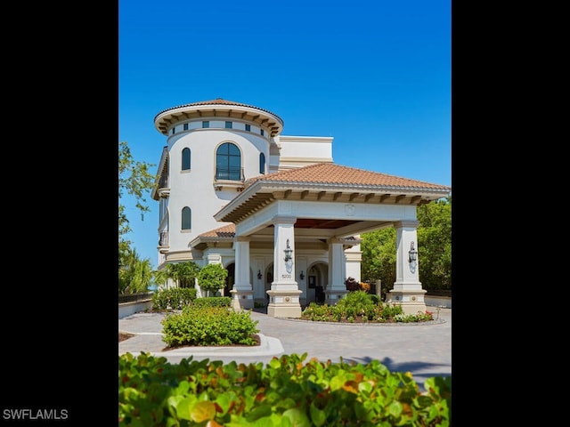 rear view of house featuring covered porch, a tile roof, and stucco siding