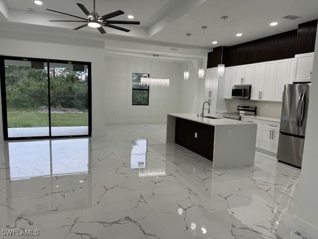 kitchen with an island with sink, sink, decorative light fixtures, white cabinetry, and appliances with stainless steel finishes