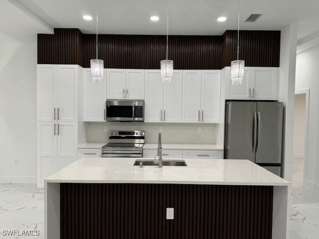 kitchen featuring pendant lighting, a center island with sink, stainless steel appliances, and sink