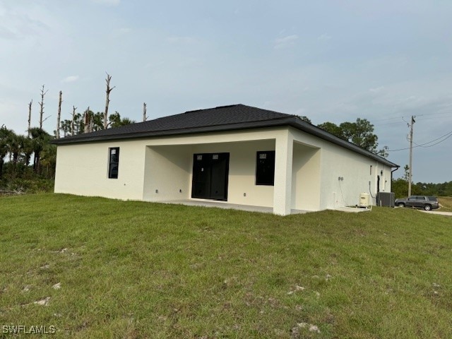 back of property featuring cooling unit and a lawn