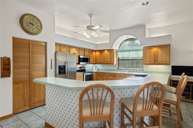 kitchen featuring appliances with stainless steel finishes, sink, kitchen peninsula, ceiling fan, and light tile patterned floors