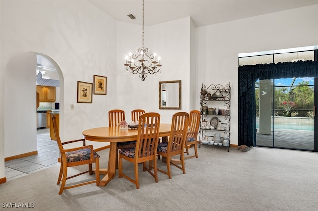 carpeted dining room with a high ceiling and ceiling fan with notable chandelier