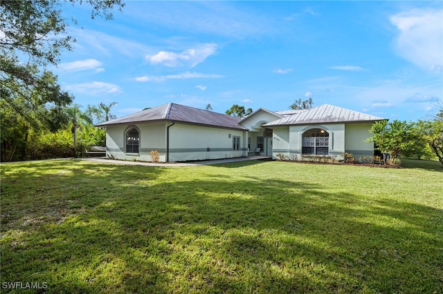 18351 Leetana Rd, North Fort Myers, FL 33917 - back of property featuring stucco siding, metal roof, and a lawn