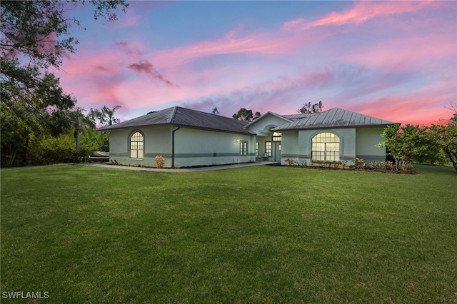 back house at dusk with a lawn