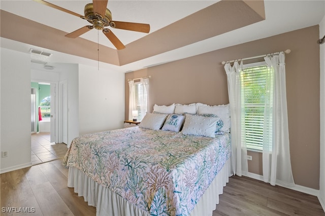 bedroom featuring hardwood / wood-style flooring, ceiling fan, and a raised ceiling