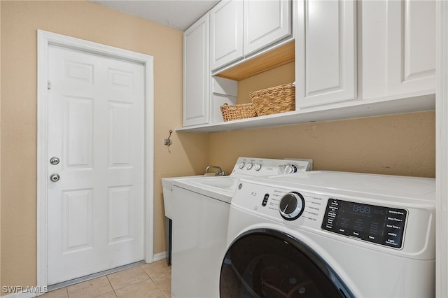 clothes washing area with cabinets, a textured ceiling, washing machine and clothes dryer, and light tile patterned flooring