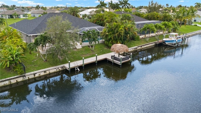 view of dock with a yard, a water view, and glass enclosure