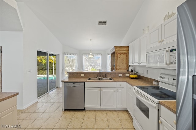 kitchen with appliances with stainless steel finishes, sink, lofted ceiling, and white cabinetry