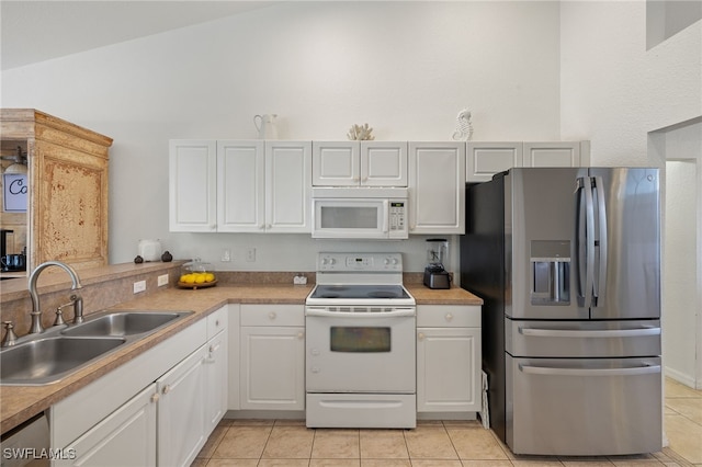 kitchen featuring white appliances, sink, light tile patterned floors, and white cabinets