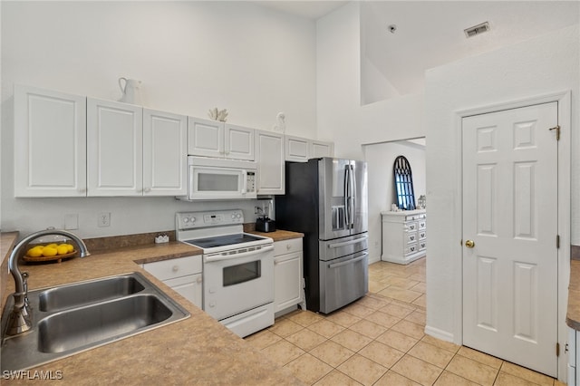 kitchen with light tile patterned floors, sink, white appliances, high vaulted ceiling, and white cabinetry