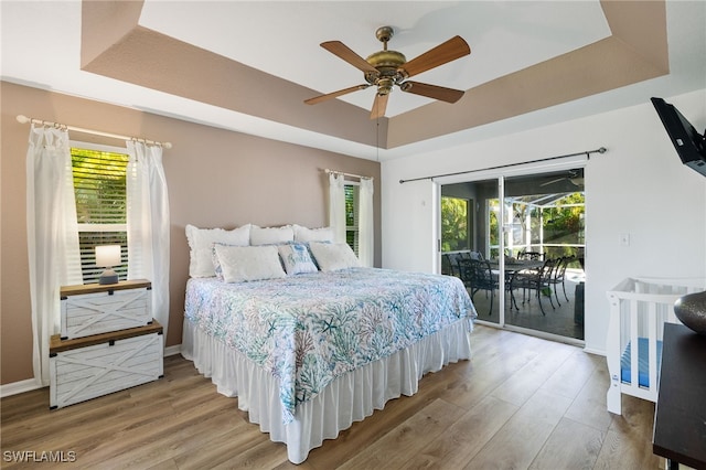 bedroom featuring a raised ceiling, access to outside, and multiple windows