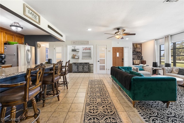 living room featuring ceiling fan, a textured ceiling, and light tile patterned floors