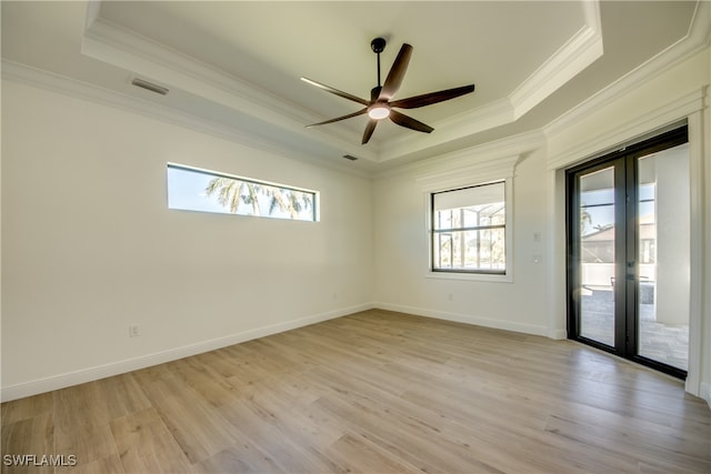 unfurnished room featuring a raised ceiling, ornamental molding, and light wood-type flooring