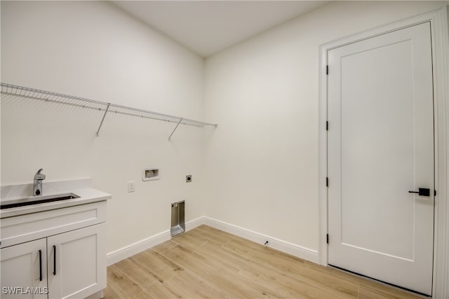 washroom with hookup for a washing machine, hookup for an electric dryer, sink, light hardwood / wood-style flooring, and cabinets