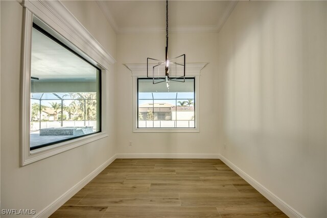 unfurnished dining area featuring ornamental molding, a notable chandelier, and light hardwood / wood-style flooring