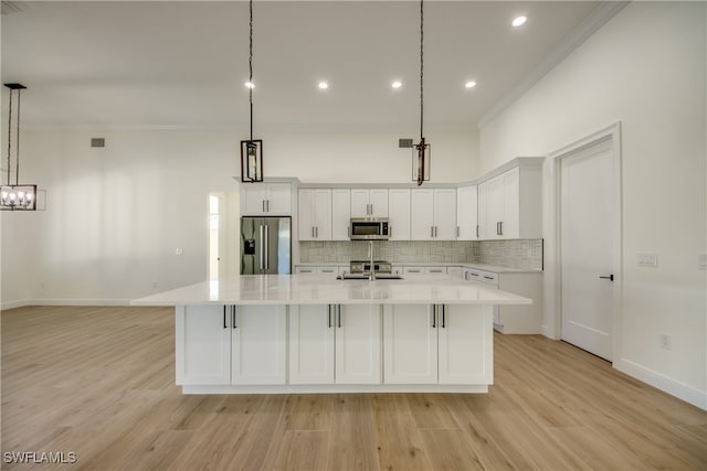 kitchen featuring pendant lighting, appliances with stainless steel finishes, light wood-type flooring, and white cabinetry