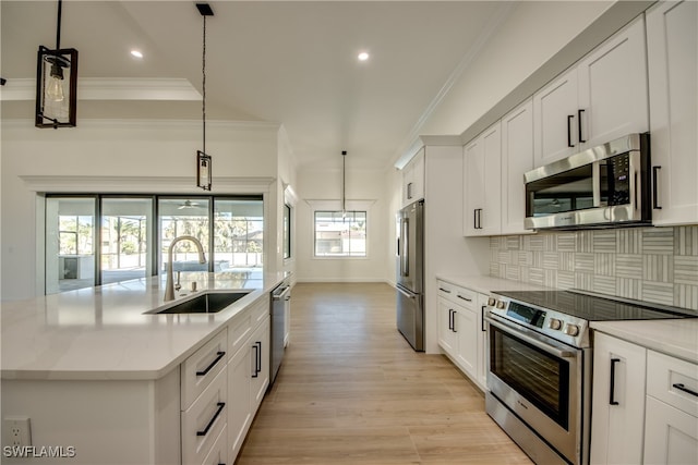 kitchen with pendant lighting, an island with sink, white cabinets, sink, and appliances with stainless steel finishes