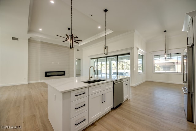 kitchen featuring decorative light fixtures, sink, stainless steel appliances, an island with sink, and white cabinets