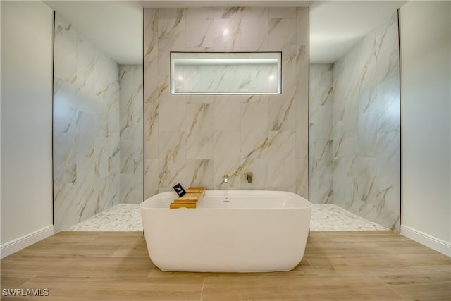 bathroom with wood-type flooring, tile walls, and plus walk in shower