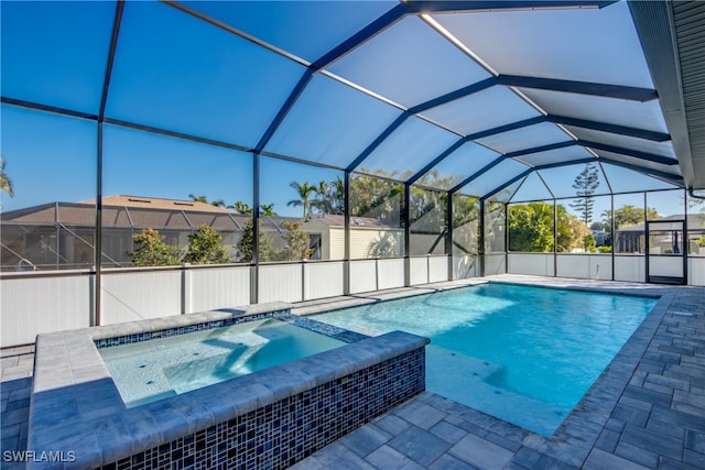 view of pool featuring an in ground hot tub, glass enclosure, and a patio area