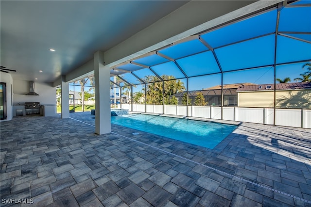 view of swimming pool featuring a lanai, an outdoor kitchen, area for grilling, and a patio area