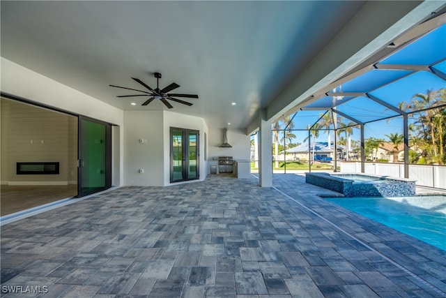 view of patio / terrace featuring ceiling fan, a swimming pool with hot tub, and glass enclosure