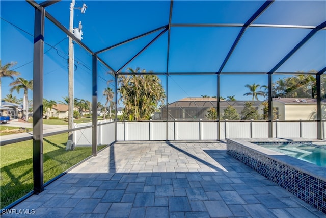 view of patio / terrace featuring an in ground hot tub and glass enclosure