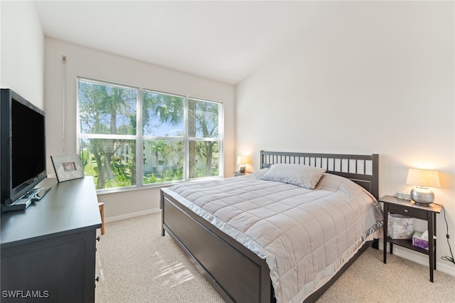 bedroom featuring light colored carpet and lofted ceiling