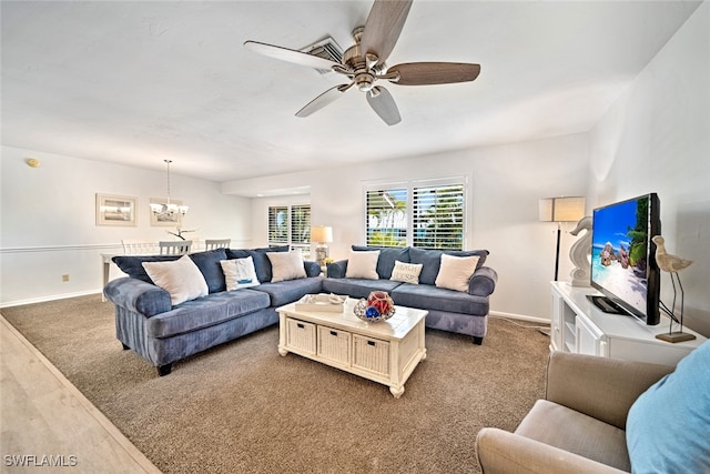 carpeted living room featuring ceiling fan with notable chandelier