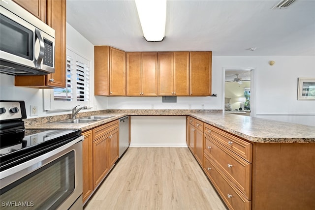 kitchen featuring ceiling fan, sink, light hardwood / wood-style floors, kitchen peninsula, and appliances with stainless steel finishes