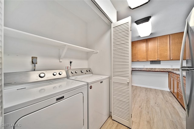 clothes washing area featuring washing machine and dryer and light hardwood / wood-style flooring