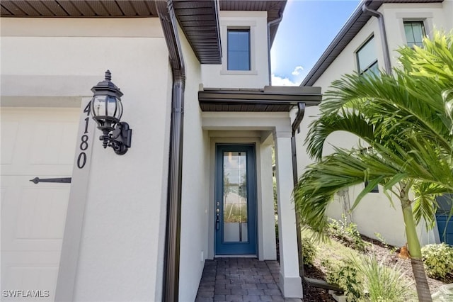 entrance to property featuring stucco siding and a garage